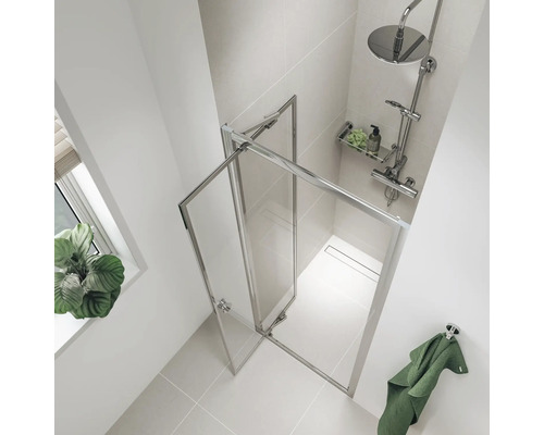 Lichte badkamer met een douchecabine van glas en metaal, een handdoek en een plant op de vensterbank.