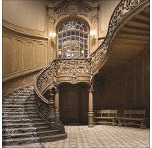 Detailopname van een kunstig versierd houten trappenhuis met wenteltrap en raam