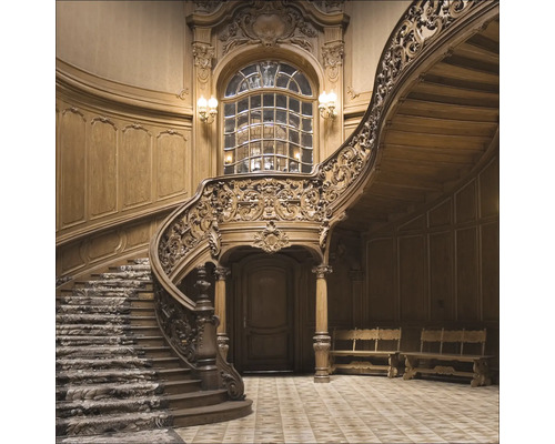 Detailopname van een kunstig versierd houten trappenhuis met wenteltrap en raam