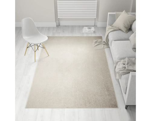 Beige tapijt in een lichte woonkamer met bank en stoel