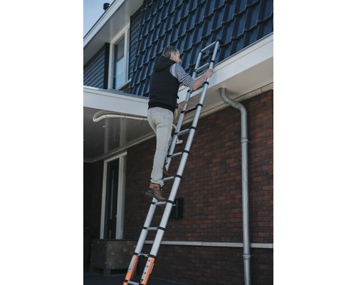 Man klimt op een telescopische ladder tegen een huis