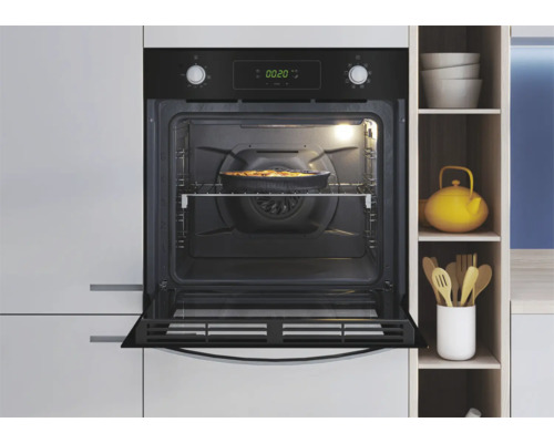 Ingebouwde oven met open deur in een lichte keuken, er staat een gerecht in de oven.