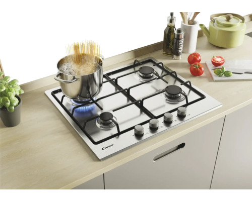 Roestvrijstalen inbouw gaskookplaat met vier pitten en een pan met kokende spaghetti op een pit.