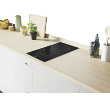 Keukenscène met een zwarte inductiekookplaat in een licht houten aanrechtblad