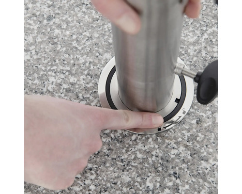 Een persoon monteert een roestvrijstalen huls op een werkblad.