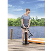 Vrouw pompt een stand-up paddleboard op met een handpomp op een houten steiger