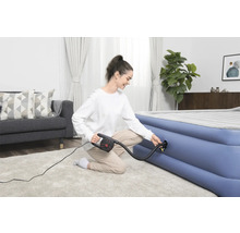 Vrouw pompt luchtmatras op met een elektrische pomp in een heldere woonkamer