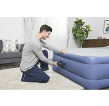 Man pompt een opblaasbaar matras op met een pomp