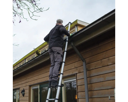 Man reinigt dakgoot met een telescoopladder aan een huis.