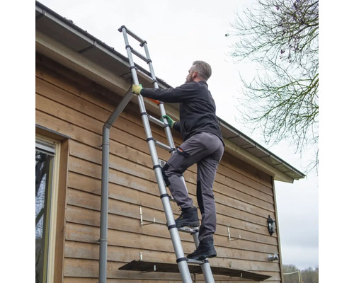 Een persoon beklimt een telescopische ladder tegen een huismuur.