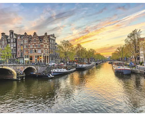 Grachtzicht in Amsterdam met woonboten en brug bij zonsondergang