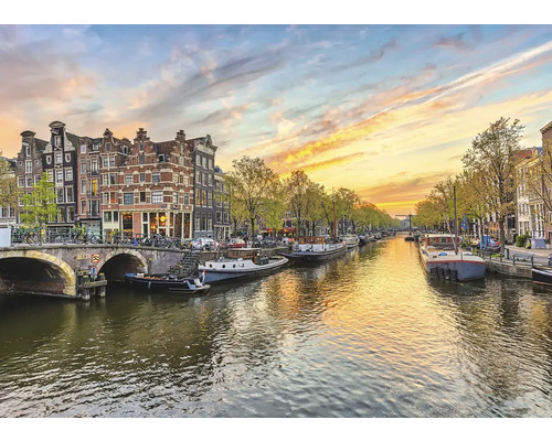 Kanaalgezicht in Amsterdam met boten, brug en historische huizen.