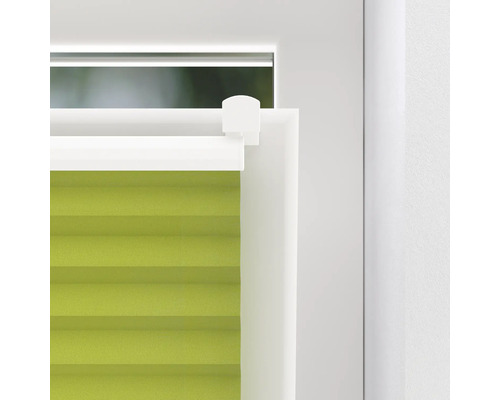 Detailopname van een groene plisségardijn aan het raam