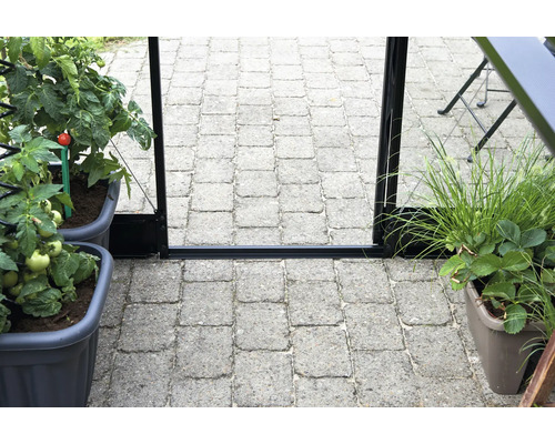 Doorkijk naar de ingang van een serre met planten in potten