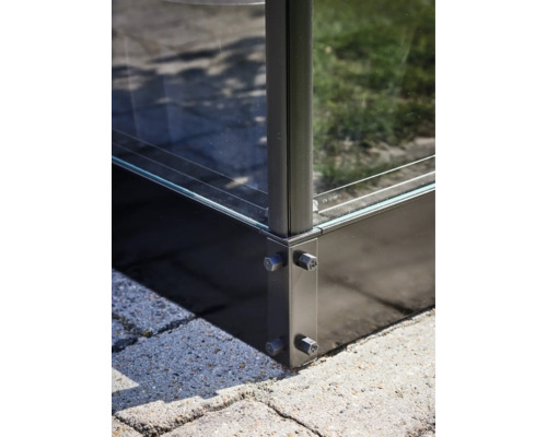 Detailopname van een glazen huis met metalen elementen en schroefbevestiging op straatstenen