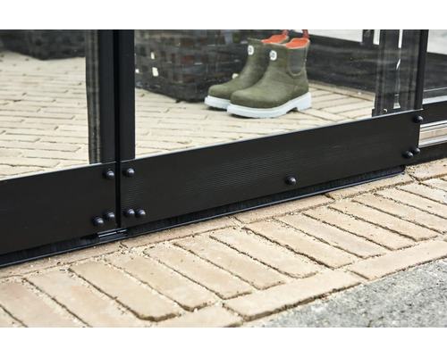 Detailopname van een kas met deurkozijn, borstelafdichting en bestrating