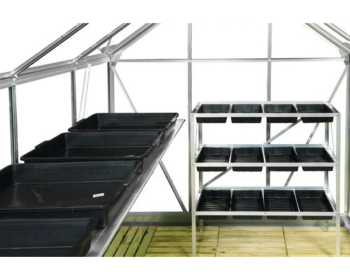 Interieur van een kas met zaaitafels en plantenbakken.