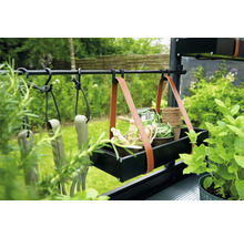 Tuinscene met tuingereedschap, plantenbakken en een hangende opbergkist met leren riemen