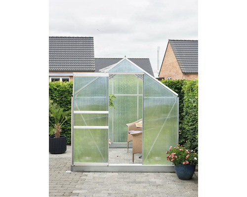 Tuinkas met open deur, omgeven door planten en tuinmeubilair