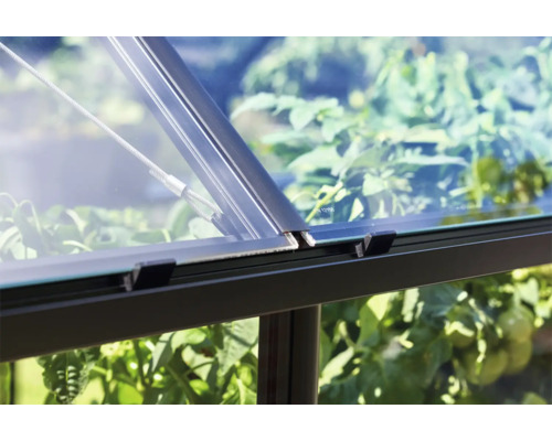 Detailopname van een kasraam met glas, metalen frame en bevestigingskabel