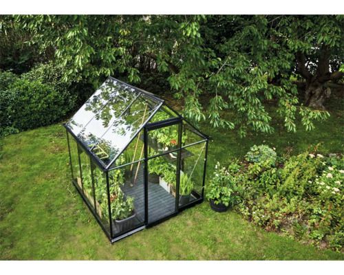 Glazen en metalen tuinkas in een tuin