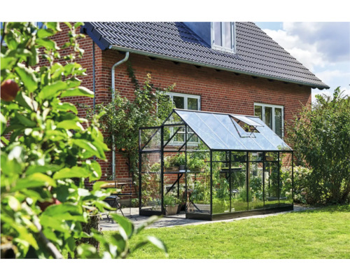 Glazen kas met metalen frame in de tuin
