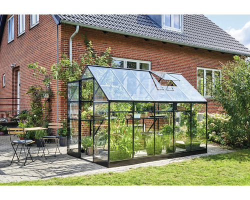 Kas met planten naast een huis met tafel en stoelen