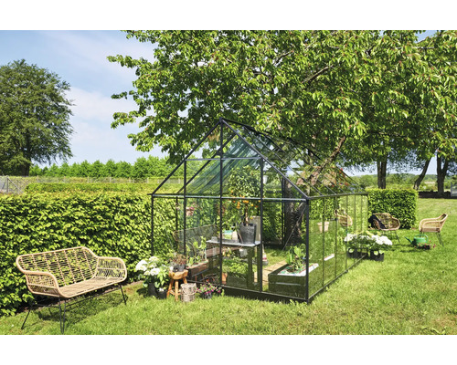 Kas met beplanting en tuinmeubelen in de tuin