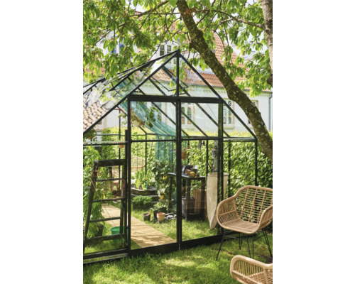 Kas in de tuin met planten, meubels en tuingereedschap.