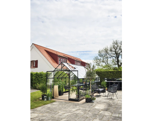 Kas met planten en tuinmeubelen in de buitenruimte