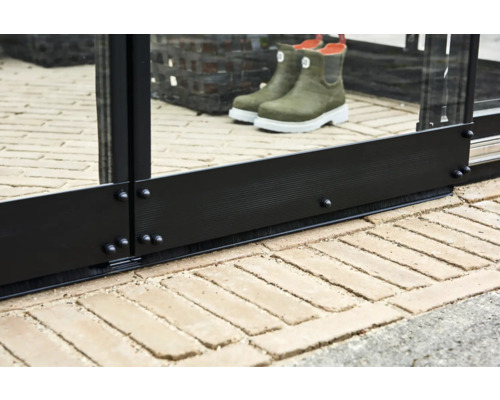 Detailopname van een kasstructuur met glas, zwarte metalen profielen en een borstelafdichting