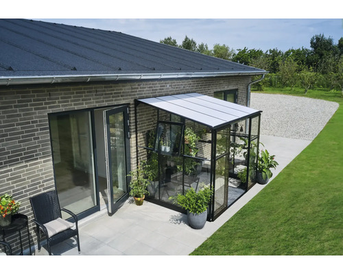 Aanbouwkas met planten aan een huis