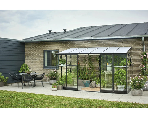 Kas met planten, tafel en stoelen in de tuin