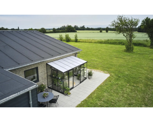 Serreaanbouw aan een huis met tuin en tafelgroep.