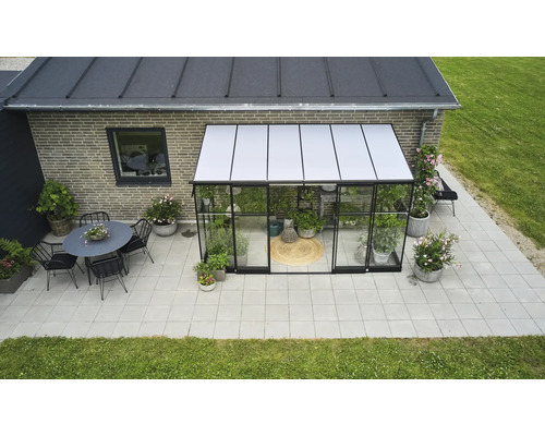 Buitenaanzicht van een kas met planten, een zithoek en een terras