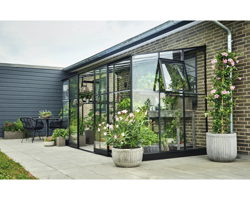 Tuin met serre, planten, tafel en stoelen.