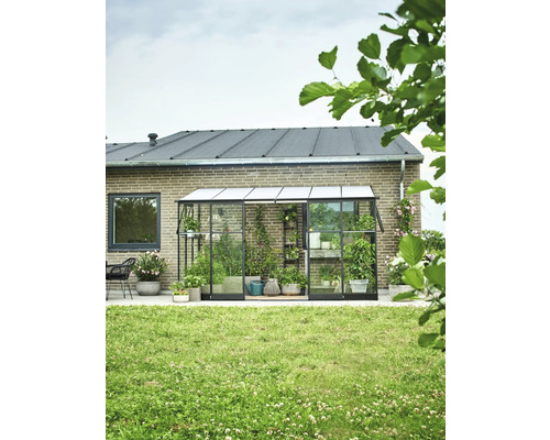 Serre aan bakstenen gebouw met planten in de tuin.