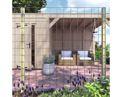 Tuinscene met draadafsluiting, houten palen en tuinhuis op de achtergrond