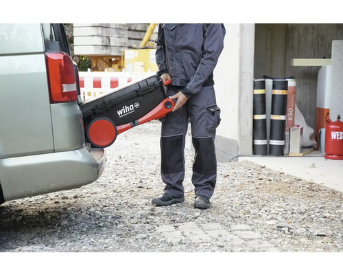 Een vakman tilt een gereedschapskoffer van Wiha in een kofferbak.