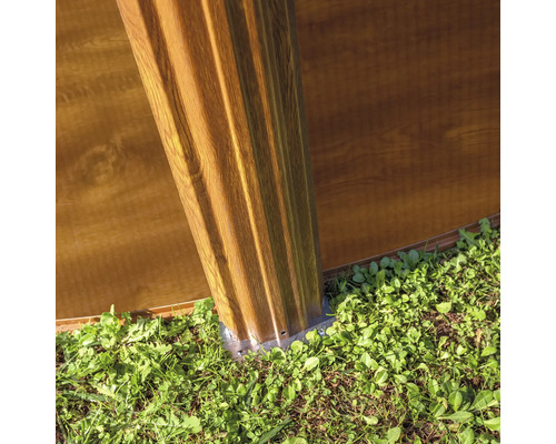 Detail van een tuinhuis met houten gevel en fundering in de tuin.