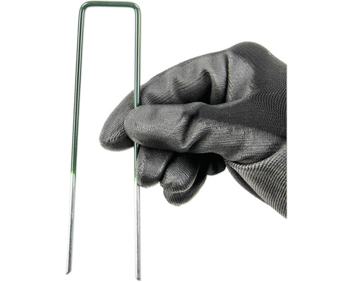 Een hand met tuinhandschoen houdt een groene gazonpen vast.