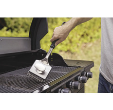 Een persoon maakt het grillrooster schoon met een grillborstel.