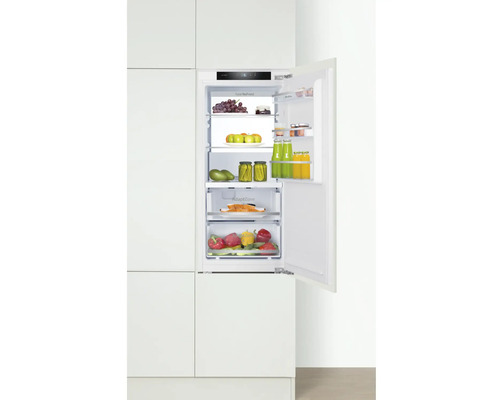 Geïntegreerde koelkast met open deur, gevuld met etenswaren in een keukenkast.