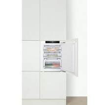 Geïntegreerde vriezer met open deur en transparante lades in een witte keuken.