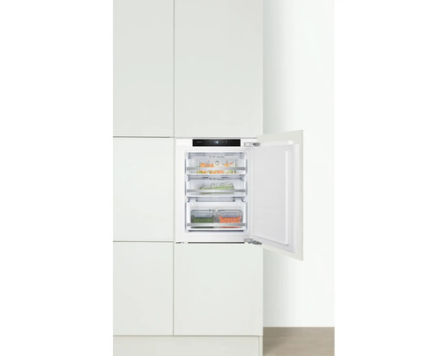 Geïntegreerde vriezer met open deur en transparante lades in een witte keuken.