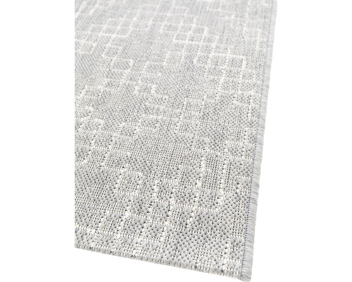 Detailopname van een lichtgekleurd tapijt met geometrisch patroon.