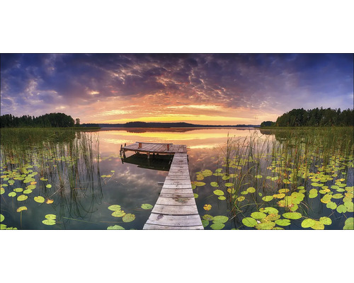 Houten steiger aan een meer met waterlelies bij zonsondergang