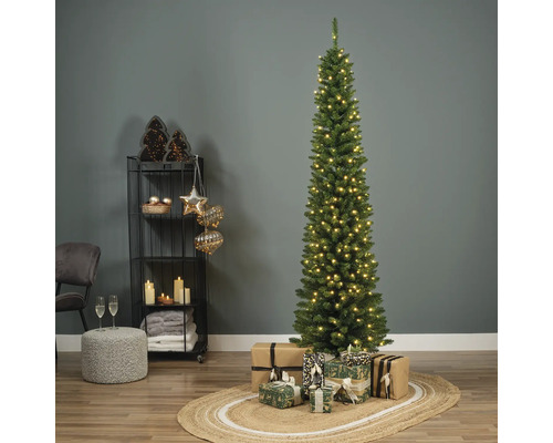 Smal verlichte kerstspar met cadeaus in een versierde kamer.
