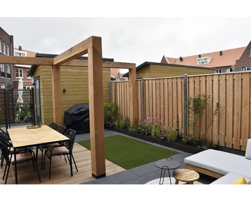 Aangelegde tuin met houten schutting, tuinhuis en zithoek