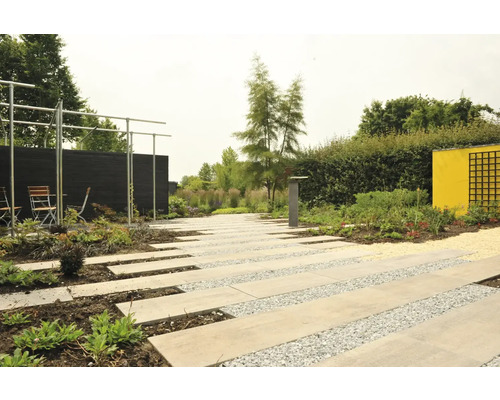 Aangelegde tuin met stenen platenpad, grindgebieden, planten, houten schutting en zithoek